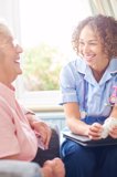 A nurse engages in conversation with an elderly woman, providing care and support in a warm, compassionate setting.